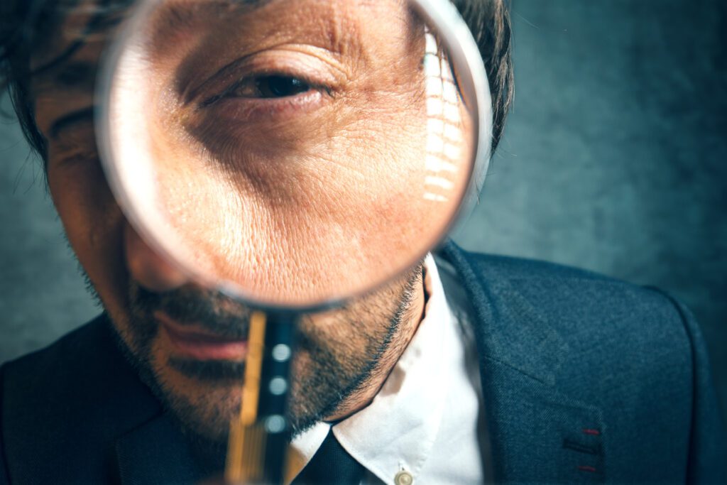 Enlarged eye of lawyer and financial auditor looking through magnifying glass, inspecting offshore company financial papers